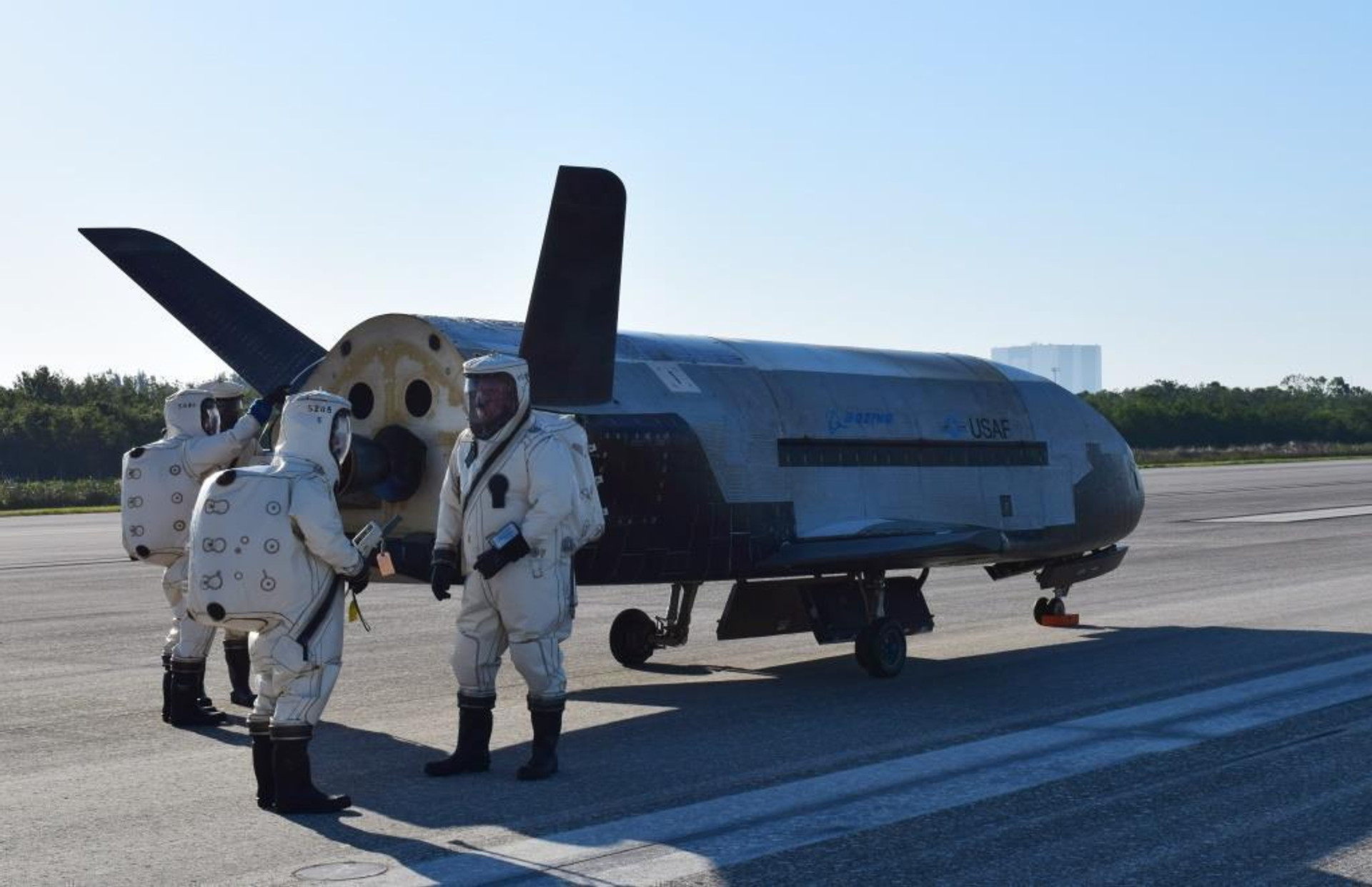 Boeing X-37B після приземлення на Shuttle Landing Facility під час місії OTV-4. Наземна команда у захисному вбранні через токсичність палива. 7 травня 2017 року